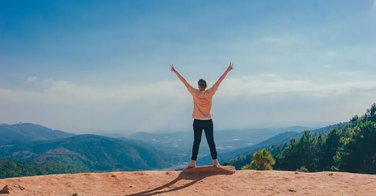 A woman stands victoriously on a mountain top celebrating success after she improved her score in her speaking exam.